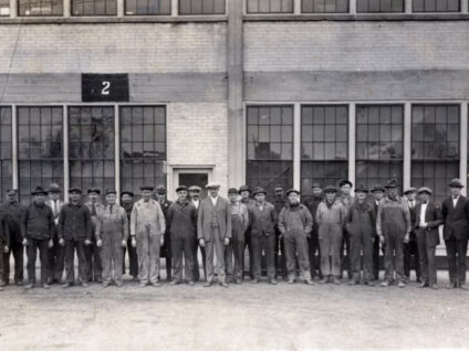 Gehl Brothers and their shop foreman in front of the Gehl Company plant in 1912 located in the city of West Bend, Wisconsin