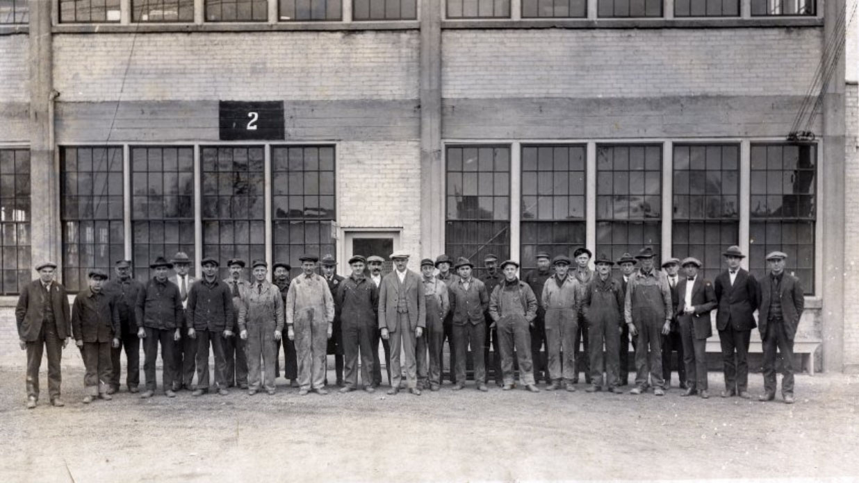 Gehl Brothers and their shop foreman in front of the Gehl Company plant in 1912 located in the city of West Bend, Wisconsin