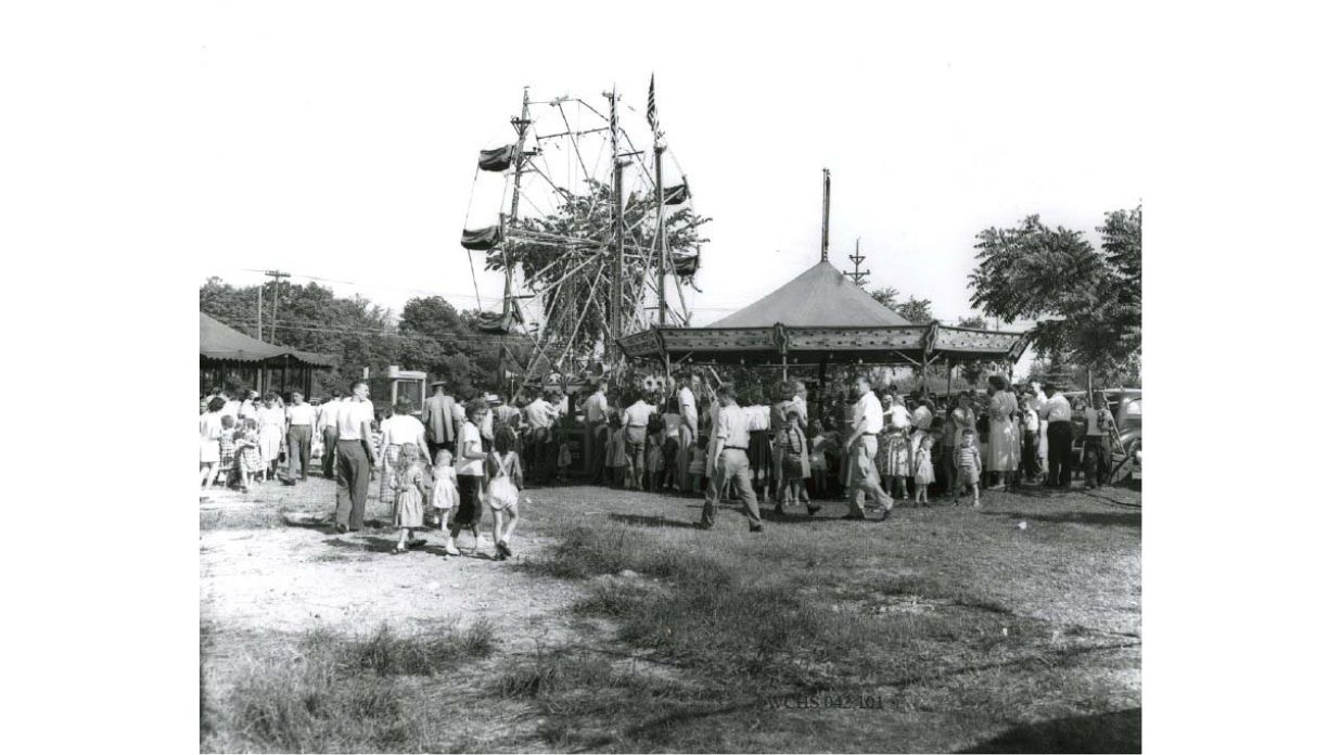 A Ferris wheel and carousel at the 1947 County Fair with The Tower Heritage Center home to the Washington County Historical Society in West Bend, Wisconsin
